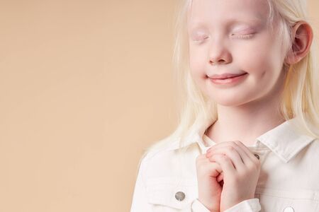 adorable beautiful child girl with white hair color and skin stand with closed eyes, dream about new toy,isolatedの写真素材