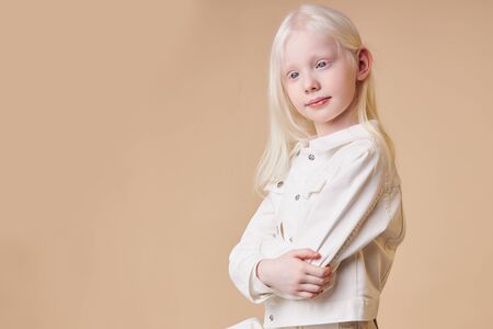 adorable albino girl 7-9 years old posing at camera isolated. shy little caucasian child with unusual natural blonde hair and white skin born with albinismの写真素材