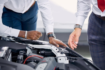 close-up photo of car hood, client and consultant talk about characteristics of car before buying