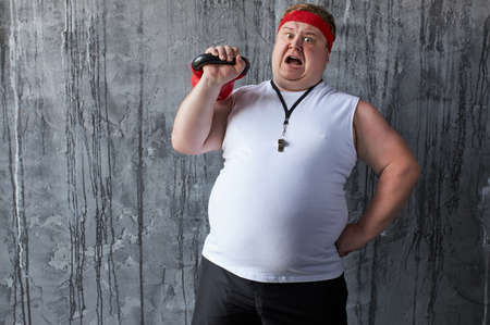 fat caucasian strong male shows his competence with the use of kettlebell, posing at camera. weight loss, fitness, sport conceptの写真素材