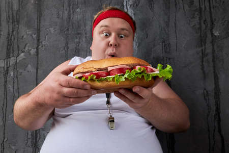 portrait of corpulent caucasian guy going to eat sandwich despite his overweight. junk food conceptの写真素材