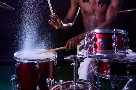 african man playing on drums in rain, water, drops on drums. percussion instrumentsの写真素材