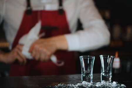Close up photo of three transparent clean short glasses with beverage isolate on dark blurred background.の写真素材