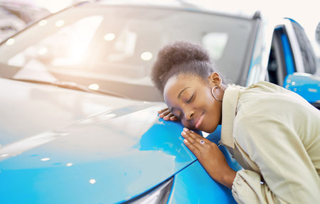 cute beautiful dark-skinned woman leaned on car, dreams about it, customer in dealership