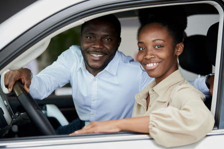 black married family examining car from inside, they are checking convenience and look characteristics of automobile in dealership, want to buy itの写真素材