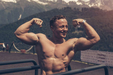 Muscular caucasian athletic crossfit sportsman with naked muscular upper body posing after regular sports session outdoors, in the highlands.の写真素材