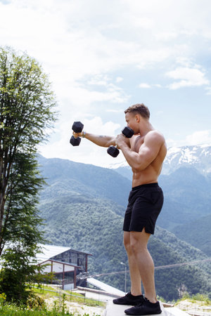 Muscular caucasian half-naked athlete with perfect shirtless body, holding dumbbells in arms raised...