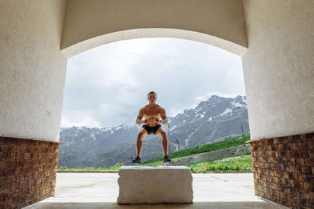 Sportsman fit male jumper doing explosive strength training jumps, crossfit fitness workout strenght power concept . Handsome strong men exercising on sky and mountain background.の写真素材