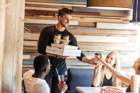Young athletic caucasian man celebrating his b-day at home ,treating friends with pizza and coffee.の写真素材
