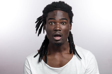 darkskinned african american man with dreadlocks shiked and looking at canera