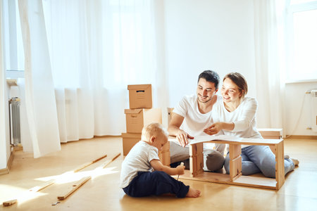 Couple with little boy assembly furniture after moving in new home