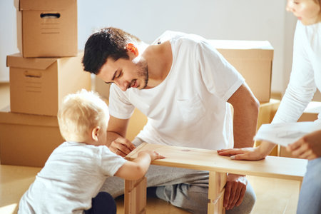 Couple with little boy assembly furniture after moving in new home