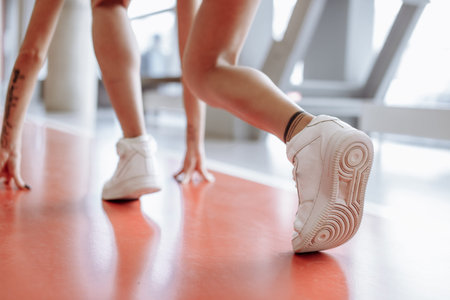 close up female runner legs on red track in white sport boots