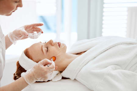Doctor applies Hydro gel Mask on the woman. Before young woman receiving laser treatment.の写真素材