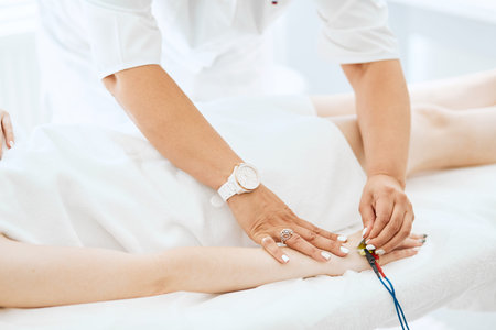 Close-up of a beautician s hand giving electrodes therapy on young womans hand in clinic.
