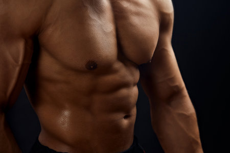 close up cropped portrait of muscular body with perfect abs. Isolated on black background.fitness,...
