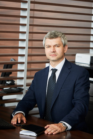 Portrait of caucasian confident businessman in classy suit at his office table with pocketbook.