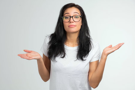 close up portrait of a pretty woman in glasses shrugging shoulders isolated on a white background.の写真素材