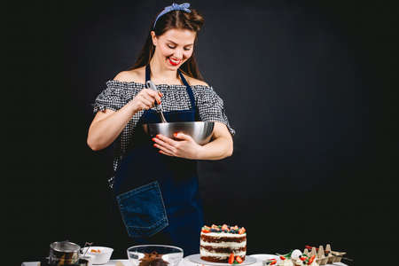 Happy vintage housewife mixing eggs for dough on black backgroundの写真素材