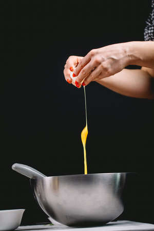 Falling eggs into stylish steel dish on black background. Baking concept.の写真素材