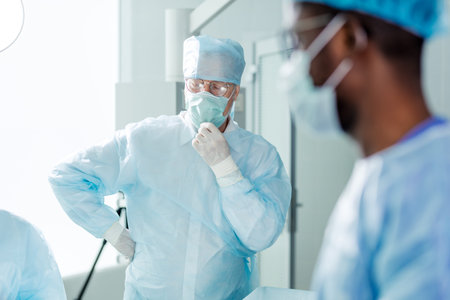 tired physician with close eyes touching surgical mask. close up photo. tiredness, blurre foreground