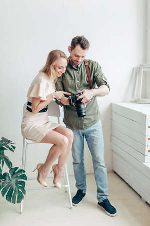 cheerful man and woman looking for good photos, full length photo, man giving advice to a modelの写真素材