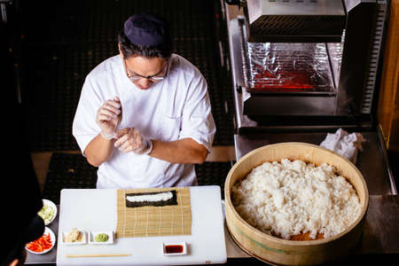 Close-up of professional chef in gloves making sushi and rolls in a restaurant kitchen.top view photo.の写真素材