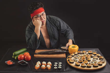 pensive serious man is fed up cooking. man hates his job. upset man in kimono leaning on the tableの写真素材