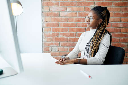 serious Afro secretary looking at the screen of the computer at workplace . close up side view shot.copy spaceの写真素材