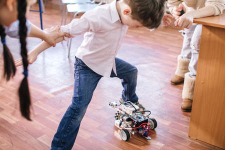 Learning process in robotics school. Curious kid playing with self made robot managed from the constructor, child learns robot constructing.の写真素材