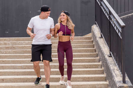 Sportive young couple running on stairs in morning city, jogging in urban area with starecases.の写真素材