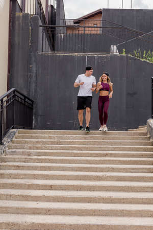 Sportive young couple running on stairs in morning city, jogging in urban area with starecases.の写真素材