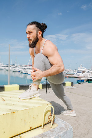 Professional muscular boxer or fighter stretching his body at the seaside, daily workouts in...