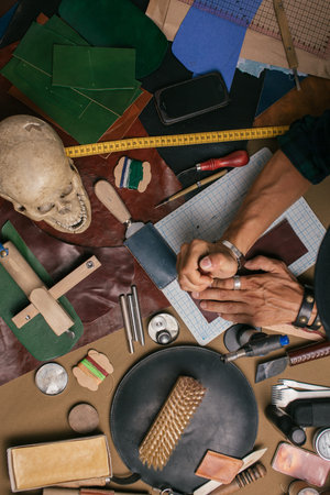 Top view of working process in leather craft workshop. Set of cobbler tools and a lot of brightly...