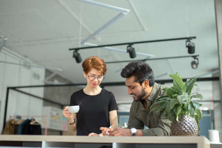 Two business people discuss meeting at table with documents and write notesの写真素材