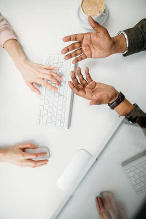 High angle of Hands of young people typing on computer in office with cup coffee close-upの写真素材