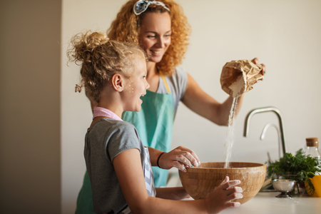 Pretty female housewife cooker wears apron and headband on head, has glad cheerful expression while...