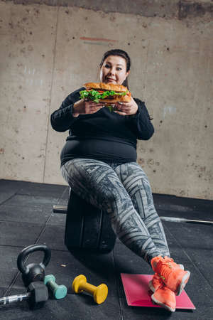 sportswoman having lunch at gym. girl cannot live without fast food . full length photoの写真素材