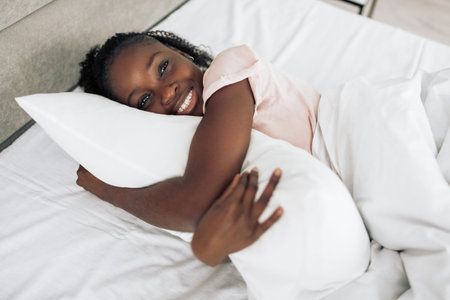 happy good looking girl embracing a pillow in the bedroom. close up shot. happiness. fun