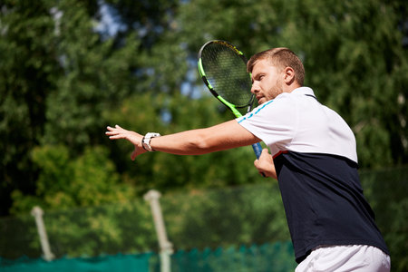 Tennis male player. Handsome bearded sportsman standing with racket in ready stance to receive ball,...