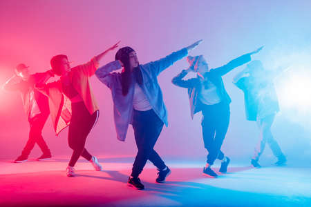 Group of male and female dancers in colorful neon light having fun dancing. Party guests enjoy atmosphere and effects in the night club. Creative fashionable neon color.の写真素材