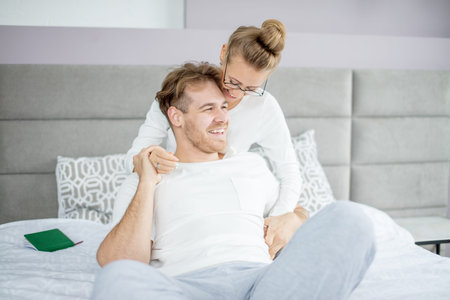 two young people laughing while sitting on the bed. happinjoice, fun, rejoice, happiness, warm ling...