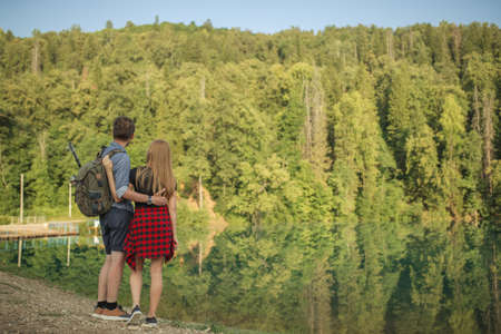 young fishman is hugging his girlfriend while resting on the nature. back view photo. copyspace. romantic landscapeの写真素材