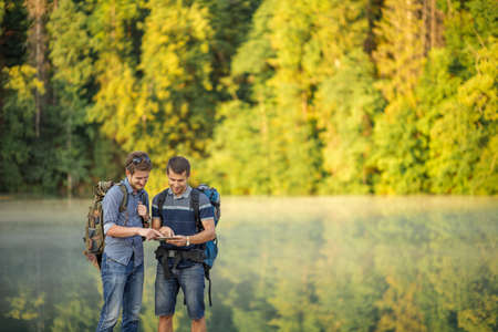 two pleasant tourists are looking at the photos which they have taken on the mountains. copy space. send e-mail. download musicの写真素材