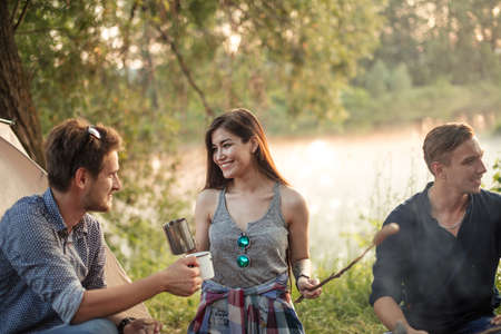 gorgeous smiling black-haired girl is having picnic with boyfriend and close friendsの写真素材