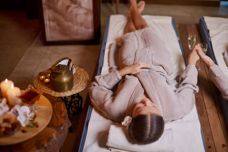 Drinking tea and relaxing in spa salon, lying down on beds and enjoy wearing bathrobe