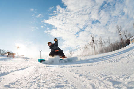 fearless snowboarder is riding fast. full length photo. photo in action. dangerous stop. man finishes snowboardingの写真素材