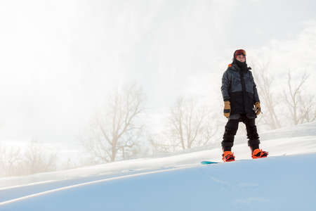 strong awesome man i stylish sportswear standing on snowboard. full length photo. copy space. eguipment, technique.の写真素材