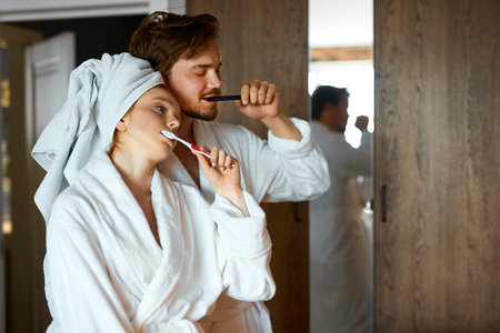 just woke up couple brushing their teeth together, woman with towel after bath stand with man...