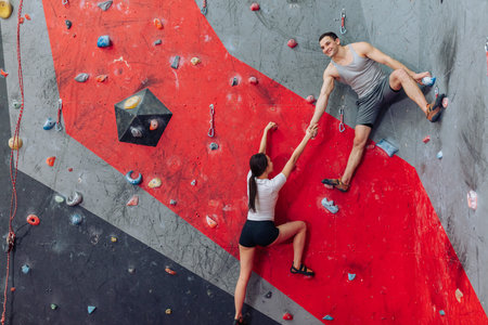 Happy male and female friends working out. Steep wall for beginners.